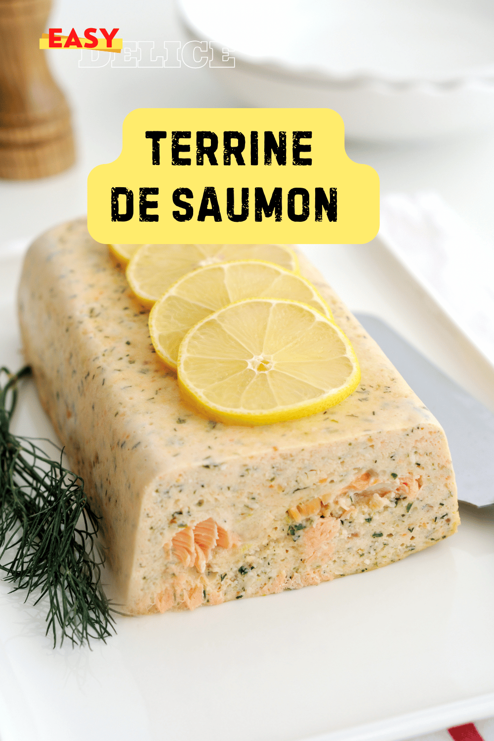 Terrine de saumon moelleuse et colorée, servie avec des tranches de citron et de l’aneth frais.