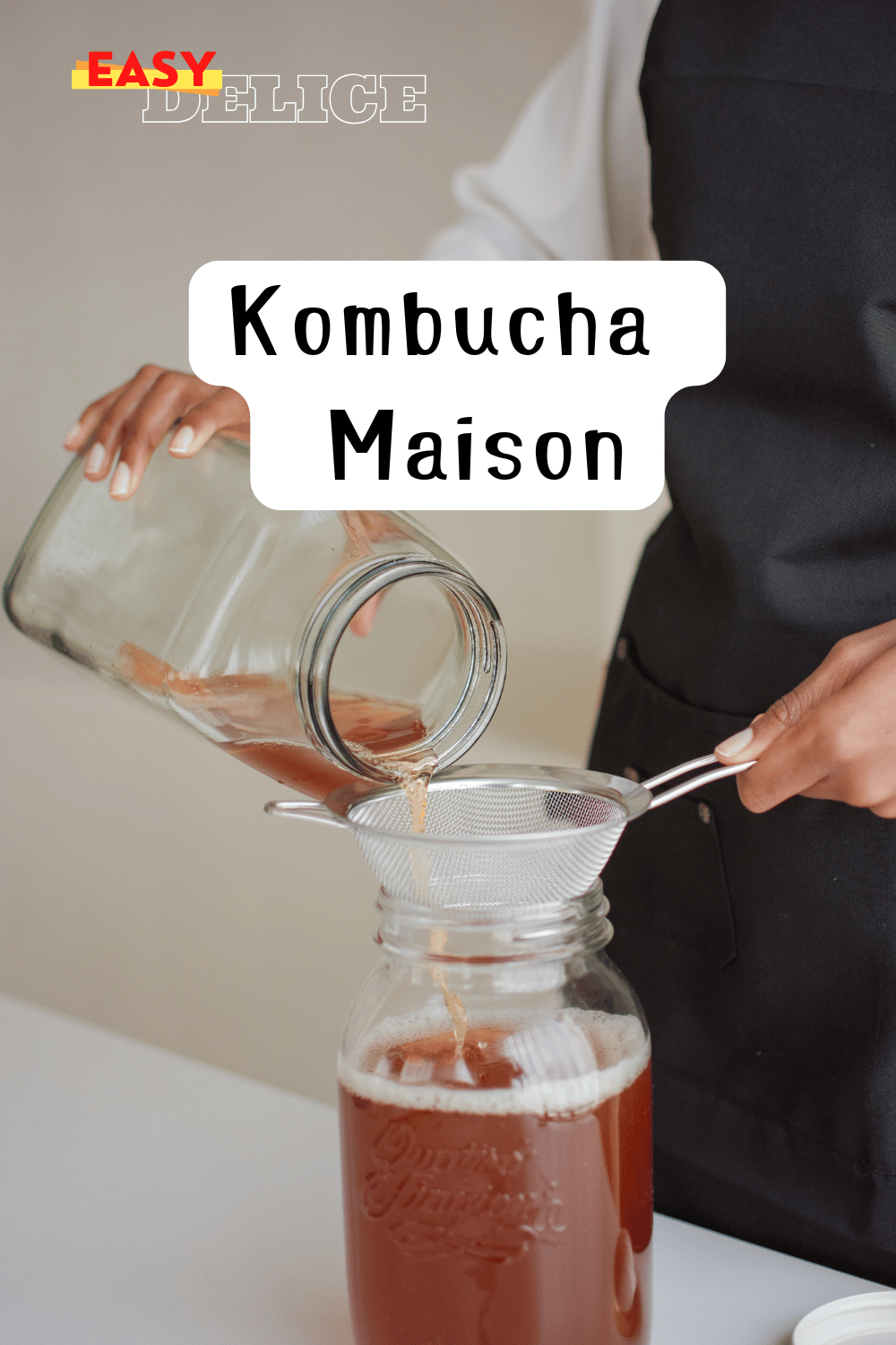 Bocal de kombucha maison en fermentation avec une SCOBY flottant à la surface.