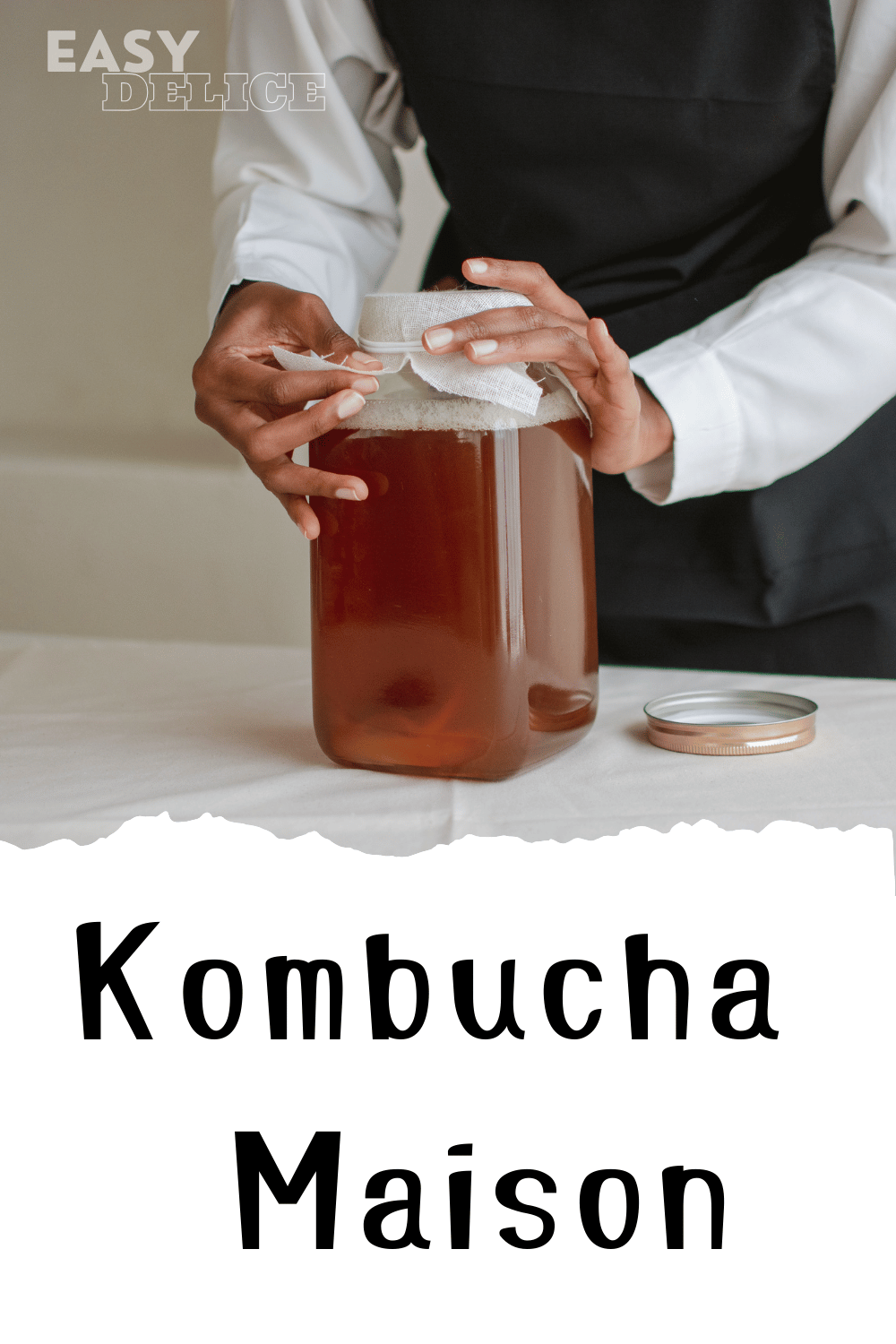 Bocal de kombucha maison en fermentation avec une SCOBY flottant à la surface.