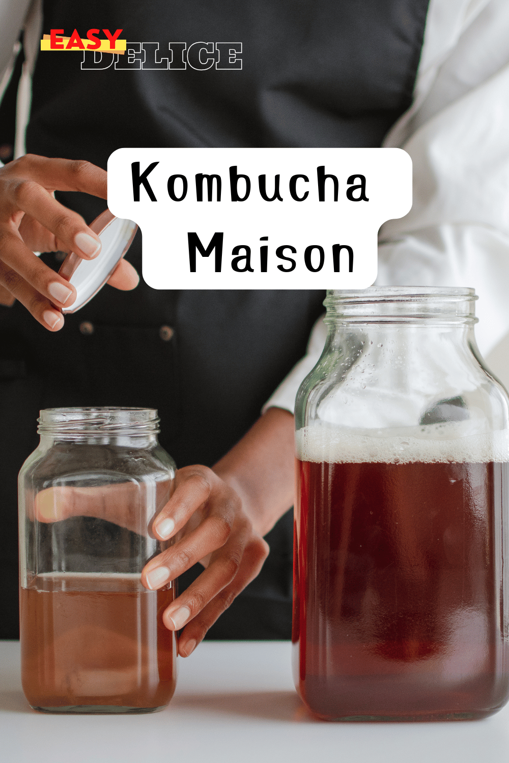 Bocal de kombucha maison en fermentation avec une SCOBY flottant à la surface.