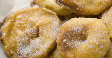 Beignets aux pommes dorés, saupoudrés de sucre glace et prêts à déguster.