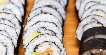 Plateau de sushis maison, avec makis et nigiris, joliment présentés sur une assiette.