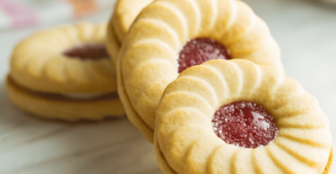 Biscuits coquins à la confiture, saupoudrés de sucre glace et remplis de confiture.