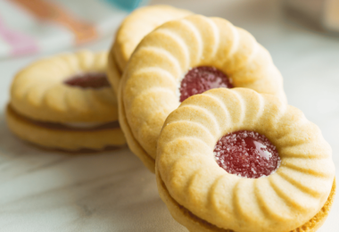 Biscuits coquins à la confiture, saupoudrés de sucre glace et remplis de confiture.