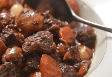 Plat de bœuf bourguignon avec morceaux de bœuf, carottes, champignons et persil