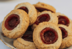 Biscuits aux amandes avec un cœur de confiture, dorés et saupoudrés de sucre glace.