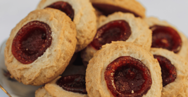 Biscuits aux amandes avec un cœur de confiture, dorés et saupoudrés de sucre glace.