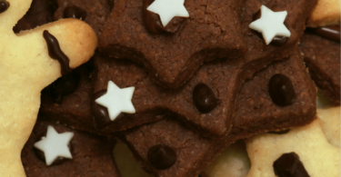 Sablés de Noël au chocolat, décorés avec du glaçage blanc et des motifs festifs.