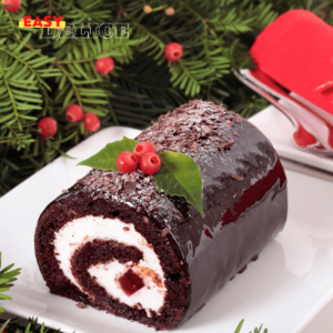 Bûche de Noël au chocolat, décorée de copeaux de chocolat et de sucre glace, sur une table festive.