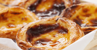 Pasteis de nata dorés et crémeux avec une touche de cannelle, prêts à être dégustés