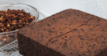 Gâteau au chocolat nappé de caramel et garni de fruits secs, prêt à être dégusté.