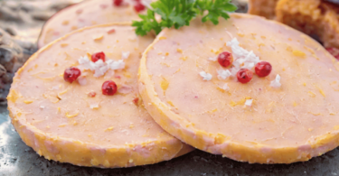 Faux gras de Noël, joliment présenté dans une terrine avec des toasts et des figues fraîches.