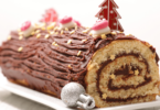 Bûche de Noël aux agrumes et amandes caramélisées, joliment présentée avec des zestes et des décorations festives.