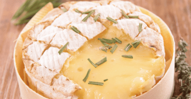 Camembert rôti au Air Fryer, doré et fondant, accompagné de pain grillé et de fruits secs.