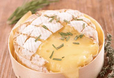 Camembert rôti au Air Fryer, doré et fondant, accompagné de pain grillé et de fruits secs.