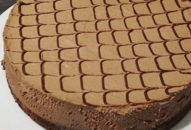 Gâteau Despacito au chocolat, nappé de ganache brillante et servi sur une assiette élégante.