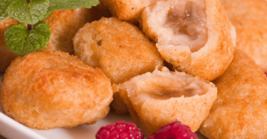 Beignets de bananes dorés et croustillants, saupoudrés de sucre glace, accompagnés d'une tasse de thé.