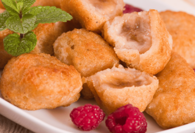 Beignets de bananes dorés et croustillants, saupoudrés de sucre glace, accompagnés d'une tasse de thé.