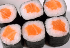 Assortiment de sushis maison avec makis, nigiris, et sashimis sur une assiette élégante.