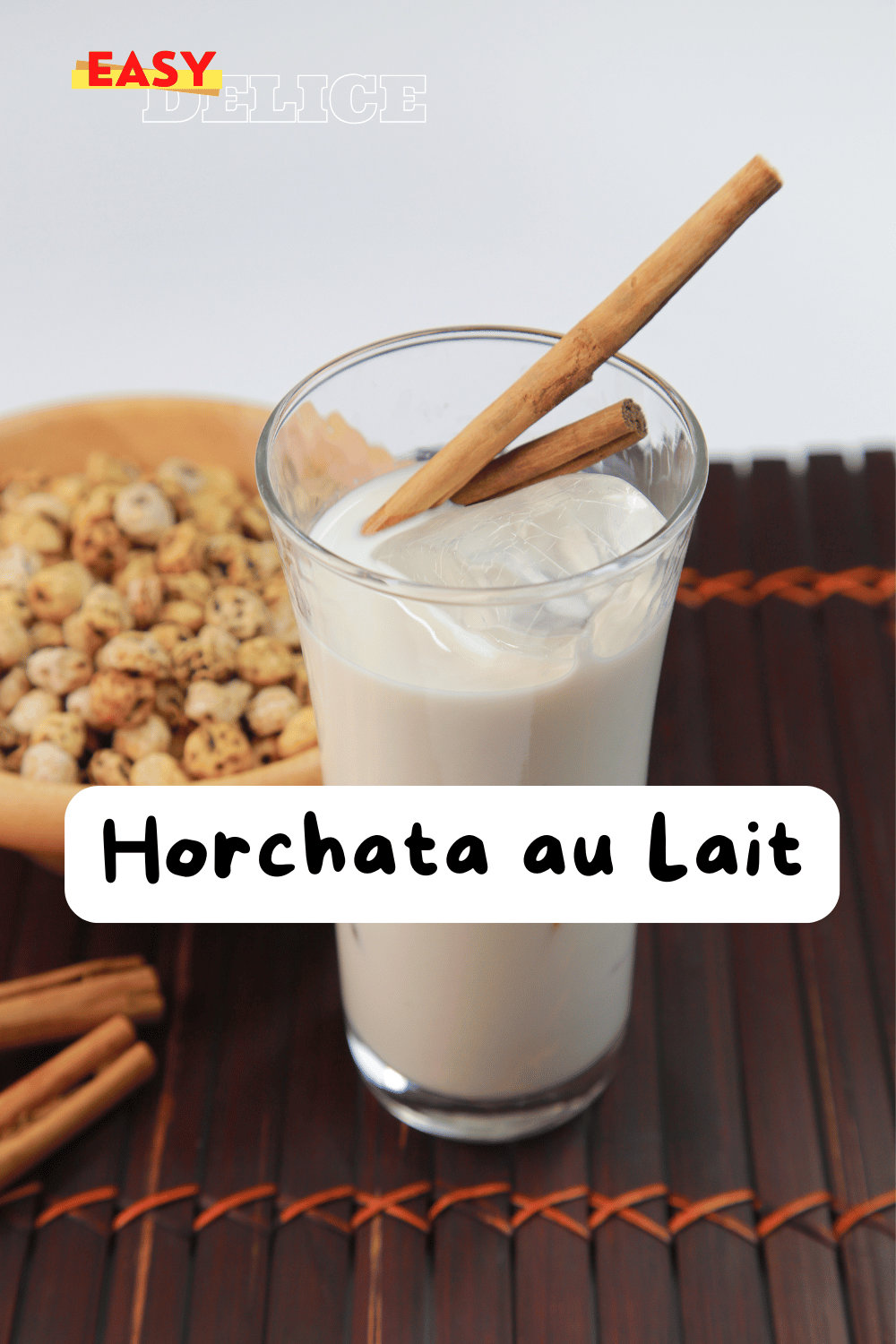 Horchata au lait servie dans un verre, décorée avec une pincée de cannelle et une tige de cannelle en garniture.