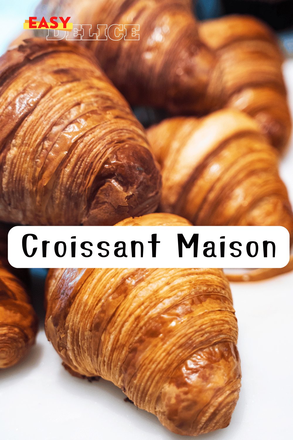 Croissants dorés et croustillants posés sur une grille de refroidissement, accompagnés d’un bol de café.