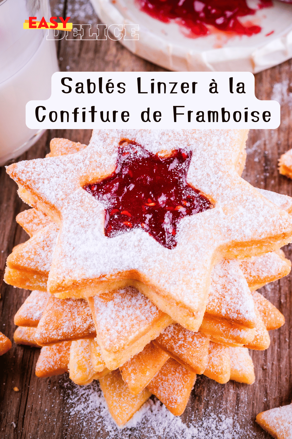 Sablés Linzer garnis de confiture de framboise, saupoudrés de sucre glace sur une assiette festive.