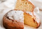 Gâteau doré et moelleux sans beurre ni huile, tranché sur une assiette ensoleillée.