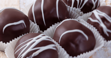 Assortiment de truffes au chocolat roulées dans du cacao, des noix et des copeaux de chocolat.