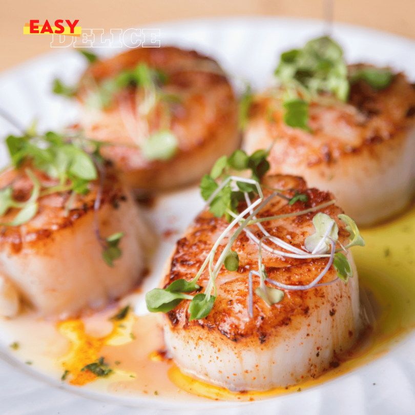 Coquilles Saint-Jacques gratinées au beurre à l’ail avec une croûte dorée de Parmesan et chapelure, servies avec des tranches de citron.