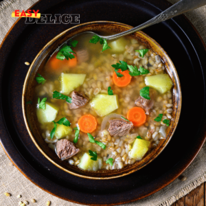 Bol de Krupnik polonais avec orge, légumes et viande, servi chaud avec du persil frais.