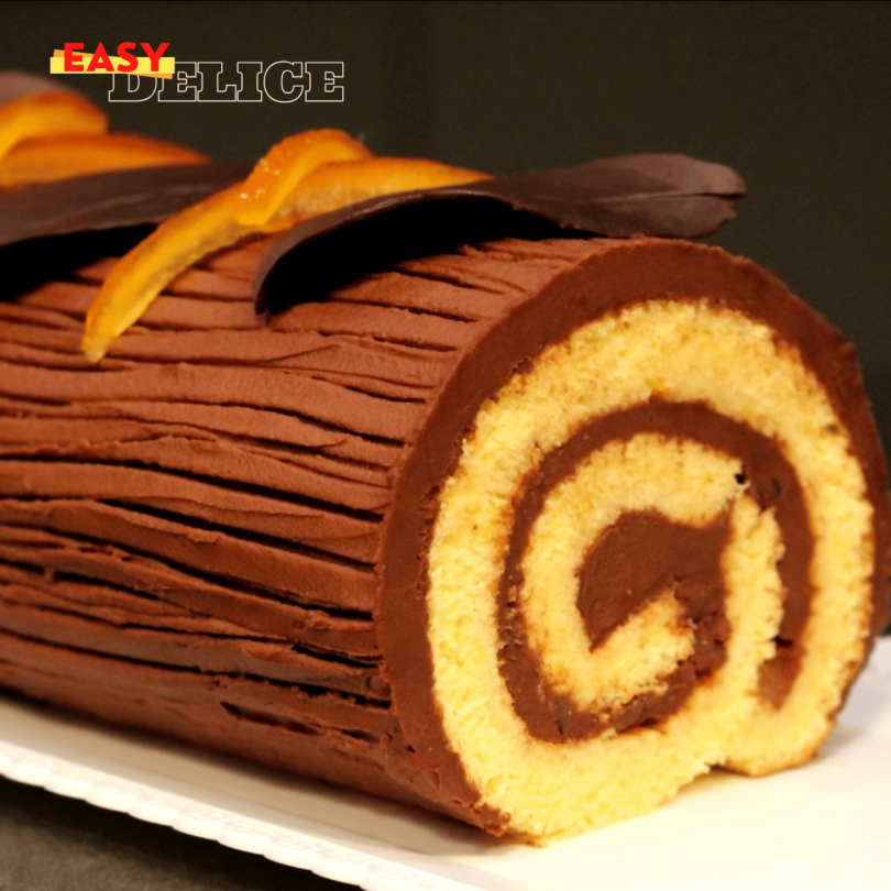 Bûche de Noël au chocolat et orange, élégamment décorée avec des zestes d’orange confite et une ganache brillante.