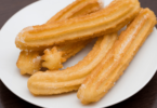 Churros faits maison avec une sauce chocolat dans un bol à côté, joliment présentés.