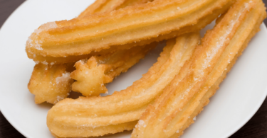 Churros faits maison avec une sauce chocolat dans un bol à côté, joliment présentés.