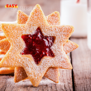 Sablés Linzer garnis de confiture de framboise, saupoudrés de sucre glace sur une assiette festive.