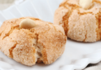 Biscuits amaretti moelleux, saupoudrés de sucre glace, servis sur une assiette.