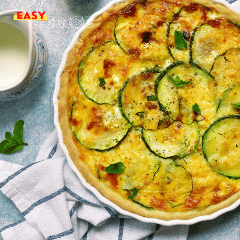 Quiche aux courgettes dorée, garnie de rondelles de courgette et d’œufs, servie avec une salade verte.