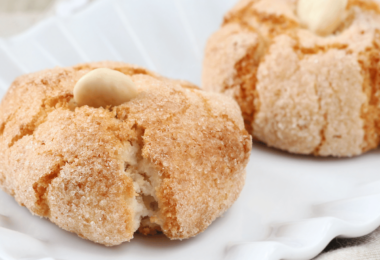 Biscuits amaretti moelleux, saupoudrés de sucre glace, servis sur une assiette.