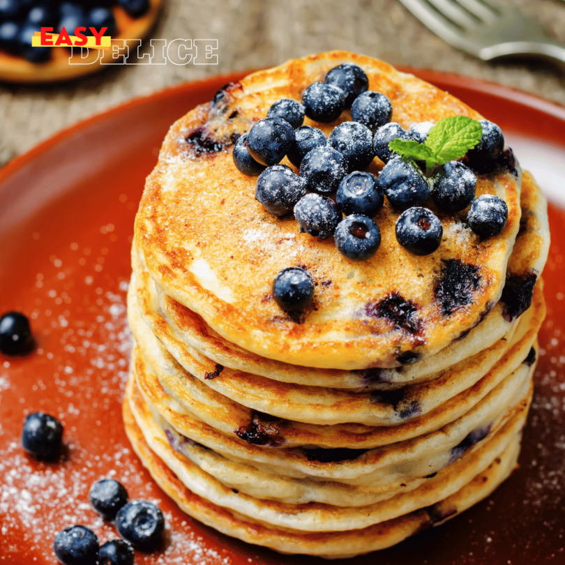 Pancakes aux myrtilles dorés, empilés, garnis de sirop d’érable et de myrtilles fraîches.