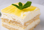 Un lemon tiramisu au lemon curd présenté dans un plat élégant, garni de zestes de citron et d'une couche crémeuse.