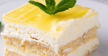 Un lemon tiramisu au lemon curd présenté dans un plat élégant, garni de zestes de citron et d'une couche crémeuse.