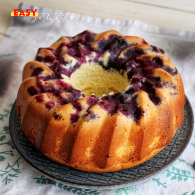 Un gâteau de Savoie aérien et doré, saupoudré de sucre glace, posé sur une assiette en porcelaine.