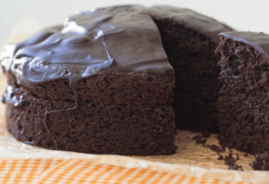 Un gâteau au chocolat sans sucre, moelleux et fondant, présenté avec une garniture de fruits rouges et une touche de cacao en poudre.