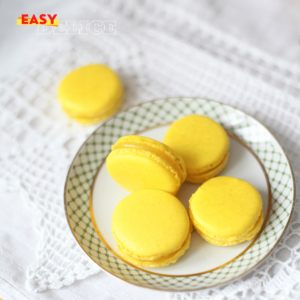 Macarons au citron jaunes et élégants, garnis d’une crème acidulée, prêts à être dégustés.