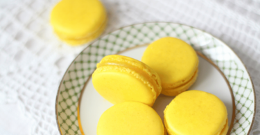 Macarons au citron jaunes et élégants, garnis d’une crème acidulée, prêts à être dégustés.