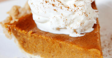 Tarte à la butternut sucrée garnie de crème onctueuse et d’épices, servie sur une table automnale.