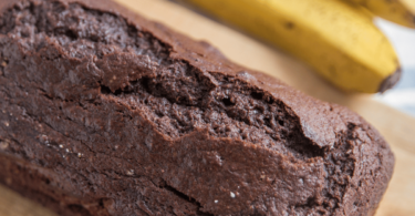 Gâteau au chocolat et aux bananes tranché, décoré avec des rondelles de bananes fraîches et des copeaux de chocolat.