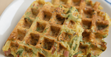 Gaufres salées à la courgette dorées, servies avec une salade fraîche et une sauce.