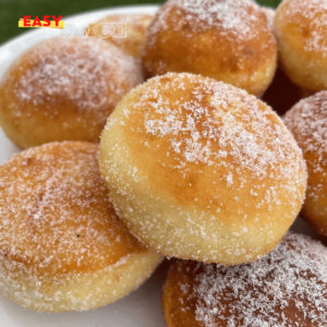 Beignets moelleux dorés, garnis de Nutella, empilés sur une assiette avec un sucre poudré scintillant.