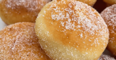 Beignets moelleux dorés, garnis de Nutella, empilés sur une assiette avec un sucre poudré scintillant.