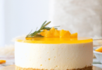 Gâteau au fromage sans cuisson avec une couche brillante de gelée d'orange, joliment présenté sur un plat de service.